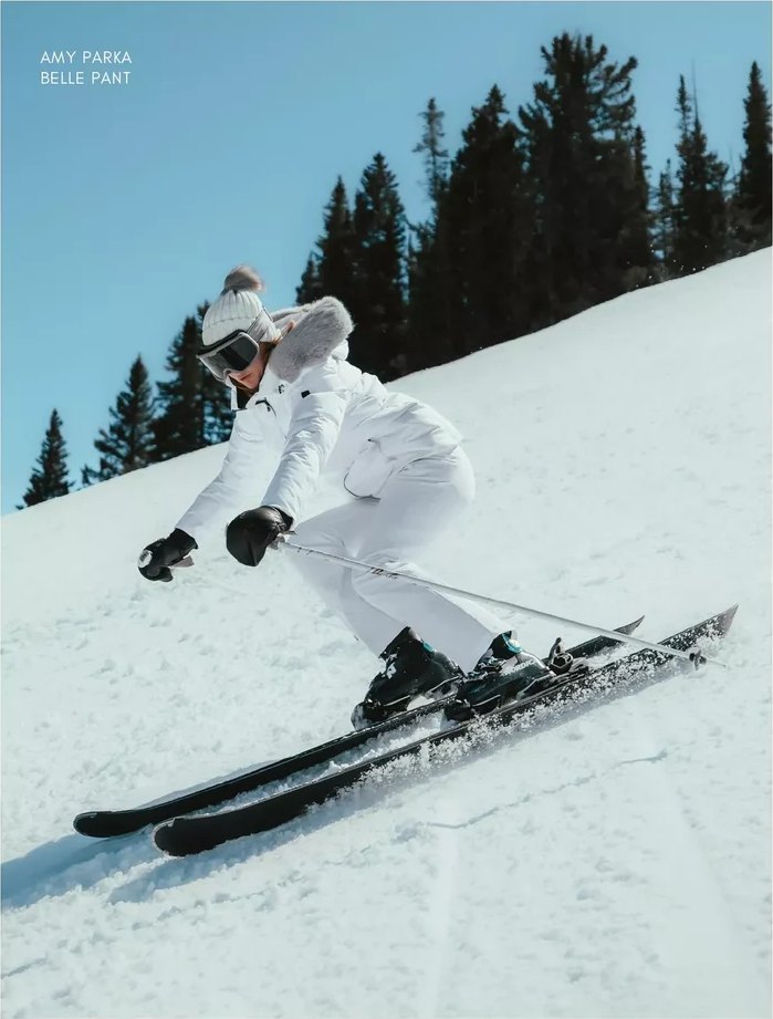 Skier in a white parka and pants carving a groomed run