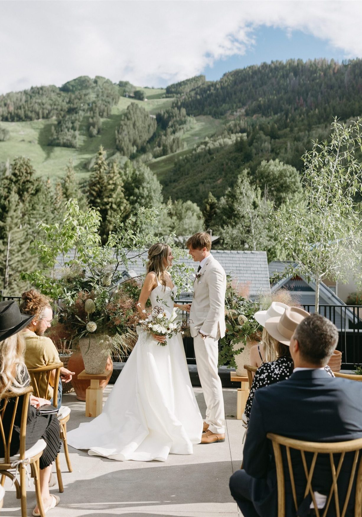 Bride and groom exchanging vows on a terrace with a green mountain behind
