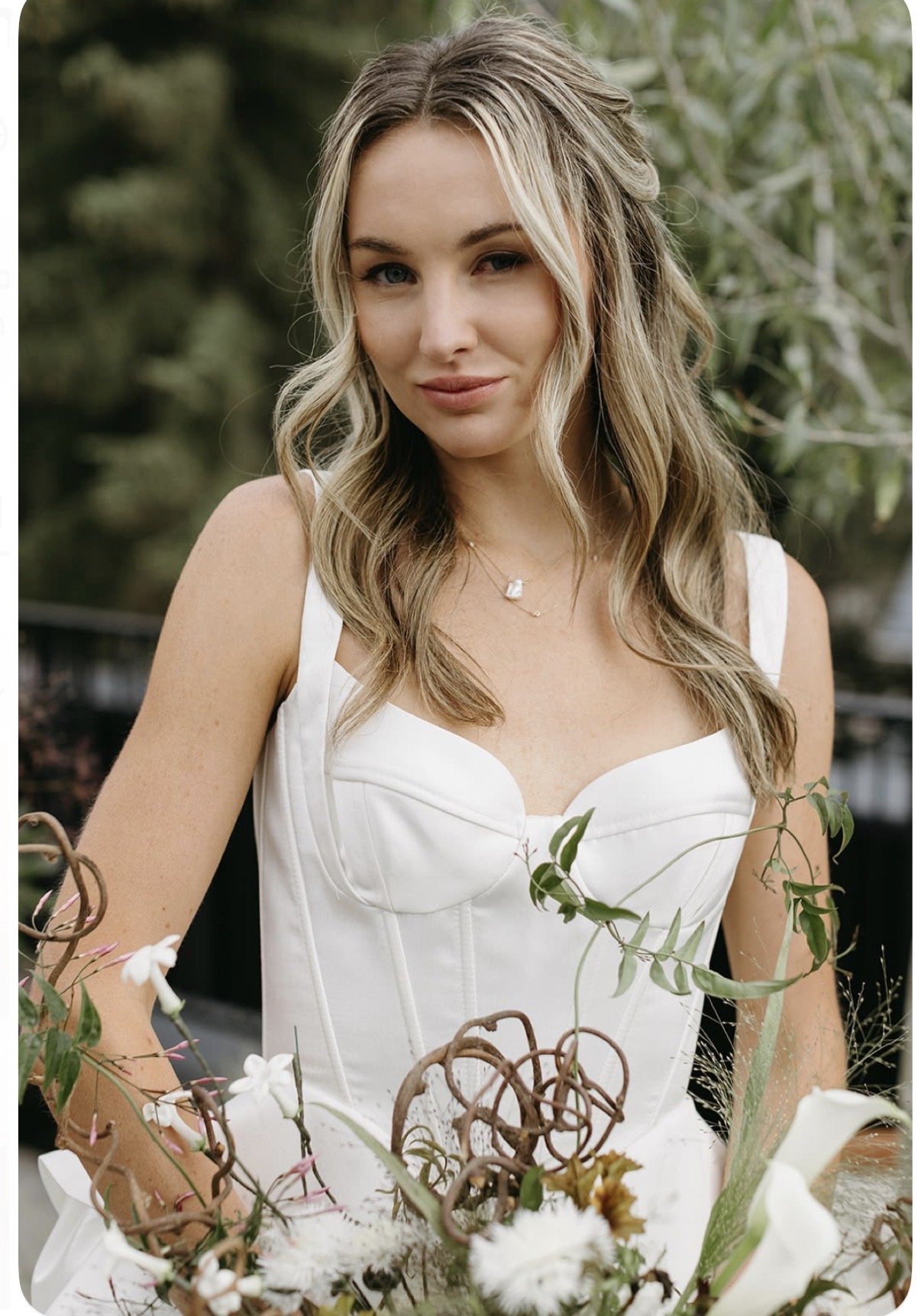 Close portrait of a bride in a corset gown with a sculptural bouquet